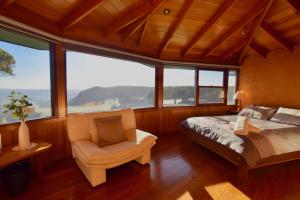 カトゥーンバにあるAmaroo Mountaintop Villaのベッドルーム1室(ベッド1台、椅子、窓付)