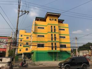 a yellow and green building on the side of a street at Meaco Royal Hotel - Malabon in Manila