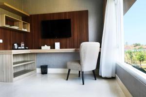 a room with a chair and a tv and a window at Mexolie Hotel in Kebumen
