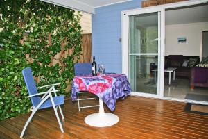 a table with a bottle of wine and two chairs at Blueys Apartment @ 192 Boomerang Drive in Blueys Beach