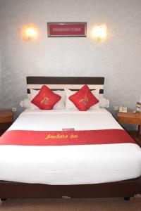 a bedroom with a large bed with red pillows at Jambura Inn in Gorontalo
