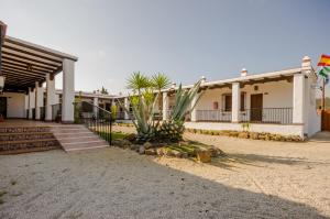 a large white building with palm trees in front of it at Hacienda Puerto Conil in Conil de la Frontera