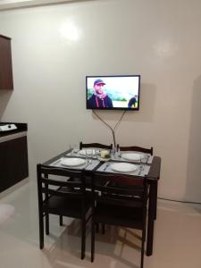 mesa con 2 sillas y TV en la pared en Jen's Paranaque City Apartment, en Manila