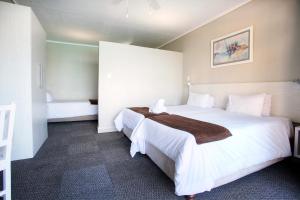 a hotel room with a large white bed in it at Marine Lodge in East London +8 photos