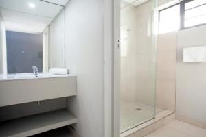 a white bathroom with a sink and a shower at Marine Hotel in East London +12 photos