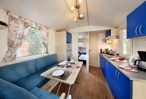 uma sala de estar com um sofá azul e uma mesa em Albatross Mobile Homes on Camping Park Umag em Karigador