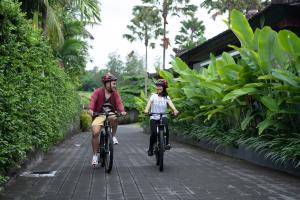a man and a woman riding bikes down a street at Natya Hotel Tanah Lot in Tanah Lot