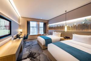 a hotel room with two beds and a desk and a tv at Mercure Chengdu Huapaifang in Chengdu