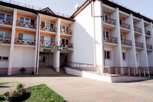 a large white building with balconies and a courtyard at Belovezhskaya pushcha Hotel №2 in Kamenyuky