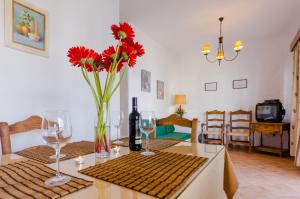 a table with wine glasses and a vase with red flowers at Hacienda Puerto Conil in Conil de la Frontera