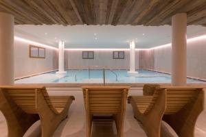 a swimming pool in a room with two chairs at Hotel Rosengarten in Madonna di Campiglio