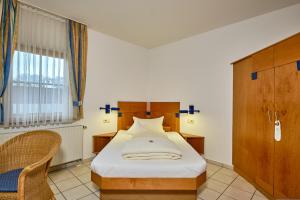 1 dormitorio con 1 cama, 1 silla y 1 ventana en Apartment Landhotel Zum Storchennest, en Bann