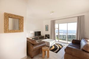 a living room with a couch and a television at Infinity Blue Luxury Accommodation in Wilderness