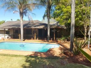 a house with a swimming pool and palm trees at Leribisi Lodge in Tierpoort