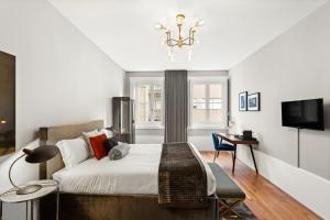 a bedroom with a bed and a desk and a television at The White Box Boutique House in Porto