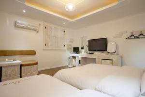 a bedroom with two beds and a desk and a television at Soul Motel in Gyeryong