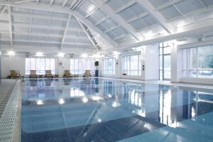 a large swimming pool with blue water in a building at Brandon Hall Hotel & Spa Warwickshire in Brandon