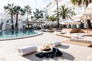 a resort with a pool and a hat and towels at Bordoy Alcudia Port Suites in Port d'Alcudia