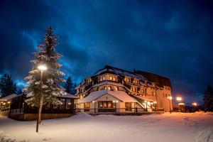 un grande edificio con un albero di Natale nella neve di Hotel Zlatarski Zlatnik a Nova Varoš