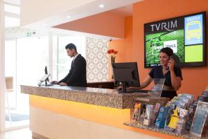 a woman talking on a cell phone at a counter at TURIM Estrela do Vau Hotel in Portimão