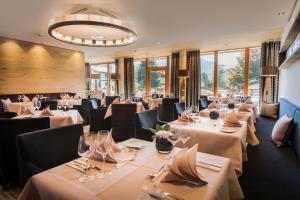 ein Restaurant mit weißen Tischen, Stühlen und Fenstern in der Unterkunft Hotel Exquisit in Oberstdorf