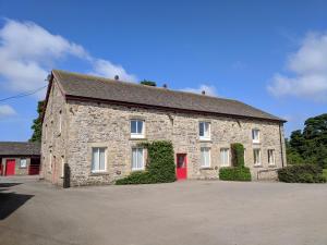 a large stone building with a red door at Mellwaters Barn Cottages in Bowes