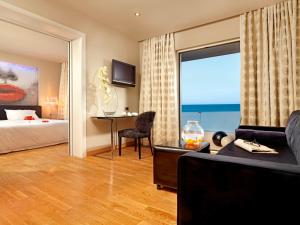 a hotel room with a bed and a desk and a window at Out Of The Blue Resort & Spa in Agia Pelagia
