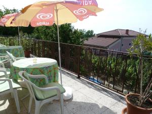 eine Terrasse mit Tischen, Stühlen und einem Sonnenschirm in der Unterkunft House Sophie in Vonyarcvashegy