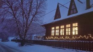 a house with christmas lights on it in the snow at Penzión Manín in Považská Bystrica