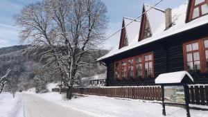 a house covered in snow next to a road at Penzión Manín in Považská Bystrica