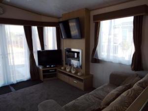 a living room with a couch and a flat screen tv at 3 Bedroom Caravan in Tattershall