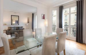 a white living room with a glass table and chairs at Résidence Charles Floquet in Paris