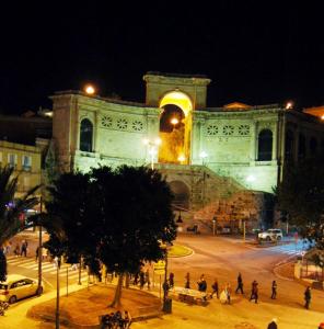 un gran edificio con gente caminando delante de él por la noche en B&B St. Remy, en Cagliari