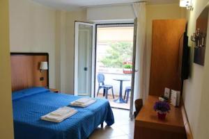 a bedroom with a blue bed and a table and a window at Hotel Mare Azzurro in Terracina