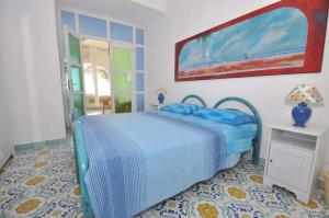 1 dormitorio con cama azul y mesa con lámpara en Casa Umberto I, en Praiano