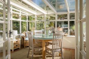 a conservatory with a glass table and chairs at Old Fox Cottage in Evesham