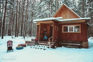 eine kleine Holzhütte im Schnee mit einem Kinderwagen in der Unterkunft Cottage Kisegach in Tschebarkul