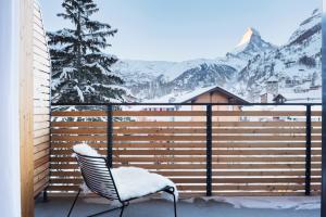 a chair on a balcony with a snow covered mountain at Haus-Ascot-Zermatt in Zermatt