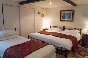 two beds in a room with two tables and two lamps at Hedley Villa Guest House in Leamington Spa