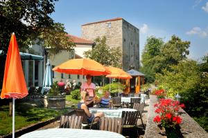 Ein Mann und eine Frau sitzen an Tischen mit Sonnenschirmen in der Unterkunft Hotel Zum Goldenen Hirschen in Freistadt