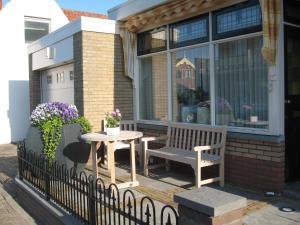 una mesa y un banco en el porche de una casa en De Oosterberg en Egmond aan Zee