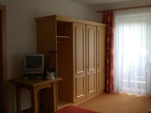 Zimmer mit einem TV, einem Schrank und einem Fenster in der Unterkunft Landhaus Auen in Neustift im Stubaital