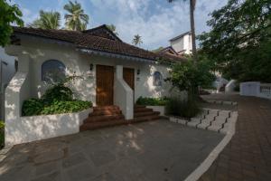 une maison avec une terrasse couverte et une allée. dans l'établissement Prainha Resort By The Sea, à Panaji