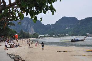 un gruppo di persone su una spiaggia con una barca di Dee Dee Sea Front a Phi Phi Don