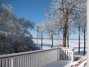 a snow covered porch with a white fence and trees at Rustherberg in Valthermond
