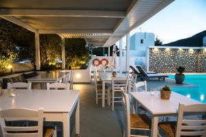 ein Restaurant mit Tischen und Stühlen und einem Pool in der Unterkunft Mouras Resort in Livadi Astypalaias