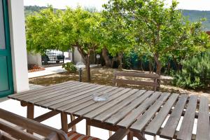 a wooden picnic table with two benches and trees at casa verdemare in Cefalù