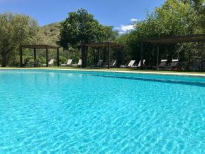 a large swimming pool with chairs and a gazebo at Hotel El Potrerillo de Larreta in Alta Gracia