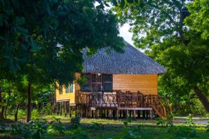 a small house with a thatched roof and a deck at Go Yala Farm Villa in Tissamaharama