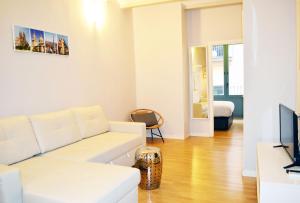 a living room with a white couch and a television at Barcelona Mercaders Apartments in Barcelona